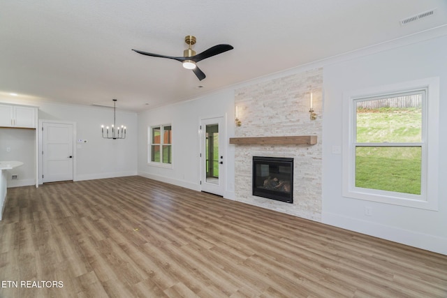 2210 Hickory Crest Ln, Knoxville, TN 37932 - unfurnished living room with crown molding, a chandelier, light wood-style flooring, a stone fireplace, and a ceiling fan