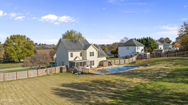 rear view of house with a fenced in pool and a yard