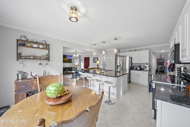 tiled dining space with ceiling fan, sink, and ornamental molding