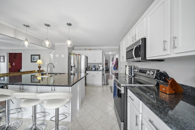 kitchen with dark stone counters, crown molding, a breakfast bar, white cabinetry, and appliances with stainless steel finishes