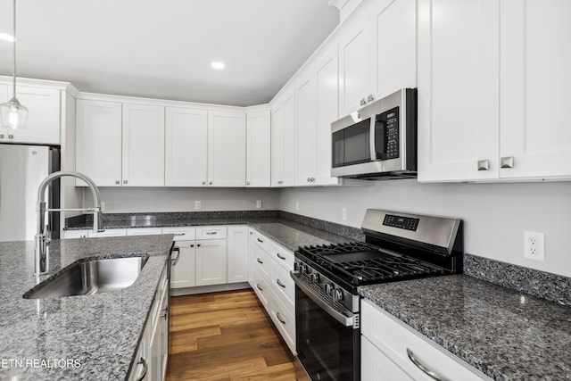 kitchen featuring sink, appliances with stainless steel finishes, white cabinets, dark wood-type flooring, and pendant lighting