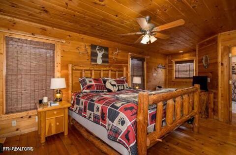 bedroom featuring wood walls, wood ceiling, hardwood / wood-style flooring, and ceiling fan