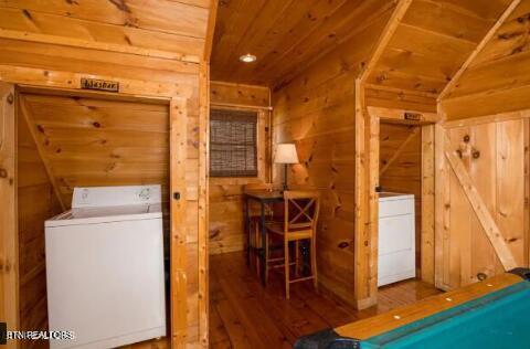 interior space featuring dark wood-type flooring, washer / dryer, wooden walls, and billiards