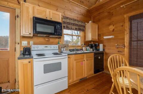 kitchen featuring wood walls, plenty of natural light, and black appliances