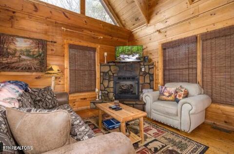 living room featuring wooden walls, lofted ceiling, wood-type flooring, and a fireplace