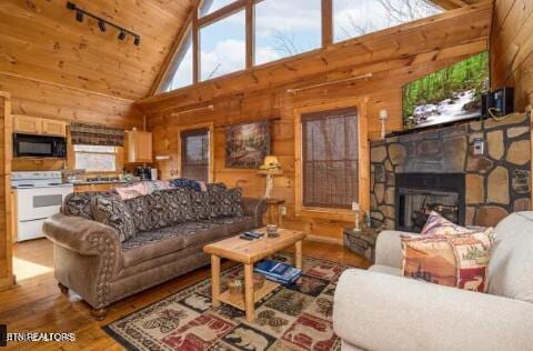 living room featuring a stone fireplace, high vaulted ceiling, wood walls, and wood-type flooring