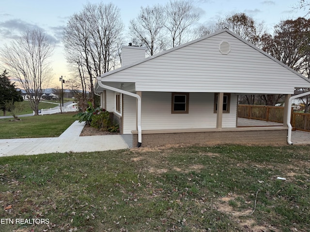 property exterior at dusk featuring covered porch and a yard