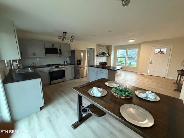 kitchen with stainless steel appliances, light hardwood / wood-style floors, sink, and backsplash