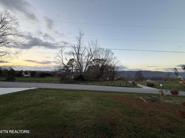 yard at dusk featuring a mountain view and a rural view