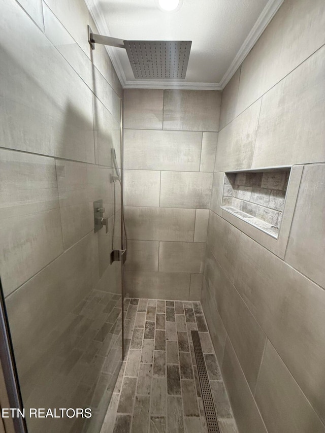 bathroom featuring ornamental molding and tiled shower