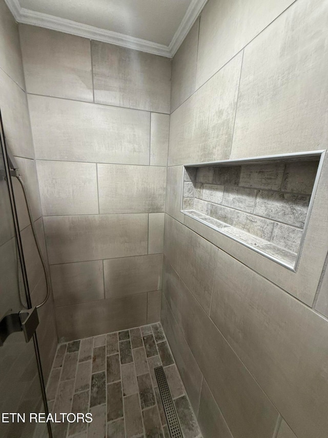 details with a tile shower and ornamental molding