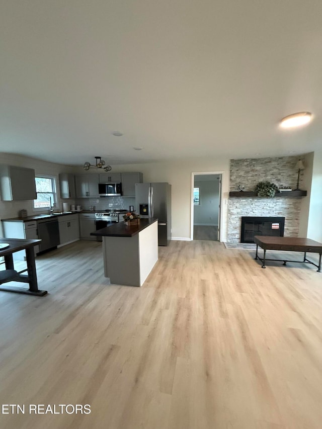 kitchen featuring a fireplace, stainless steel appliances, light hardwood / wood-style floors, and gray cabinetry