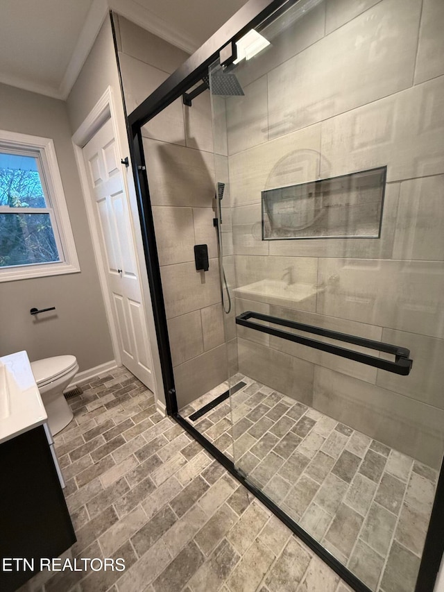 bathroom featuring a shower with door, vanity, toilet, and ornamental molding