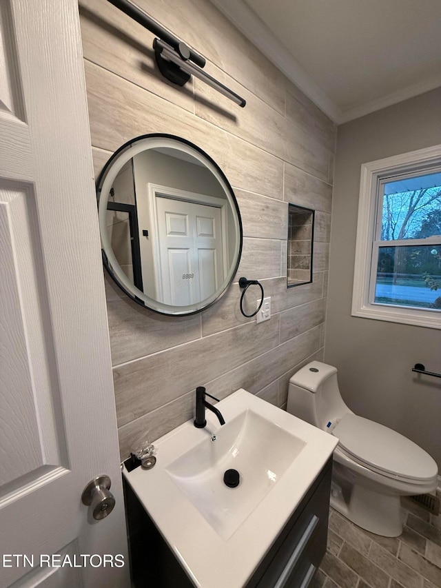 bathroom featuring tasteful backsplash, tile walls, crown molding, vanity, and toilet