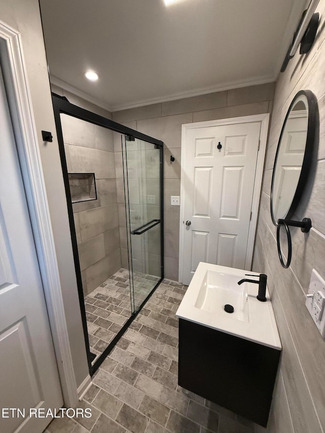 bathroom featuring ornamental molding, tile walls, vanity, and a shower with shower door