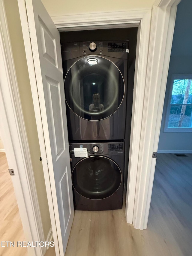 clothes washing area with stacked washer / drying machine and hardwood / wood-style floors