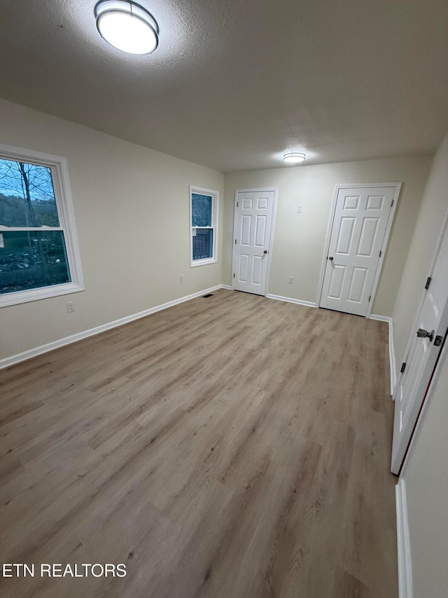 unfurnished bedroom with light hardwood / wood-style flooring and a textured ceiling