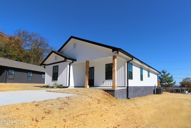 modern inspired farmhouse featuring a porch and cooling unit