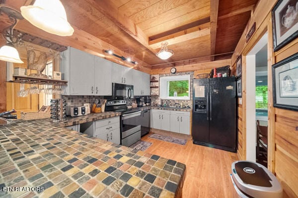 kitchen featuring light hardwood / wood-style flooring, kitchen peninsula, pendant lighting, white cabinets, and black appliances