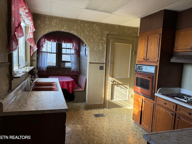 kitchen with gas cooktop, black oven, a paneled ceiling, and sink