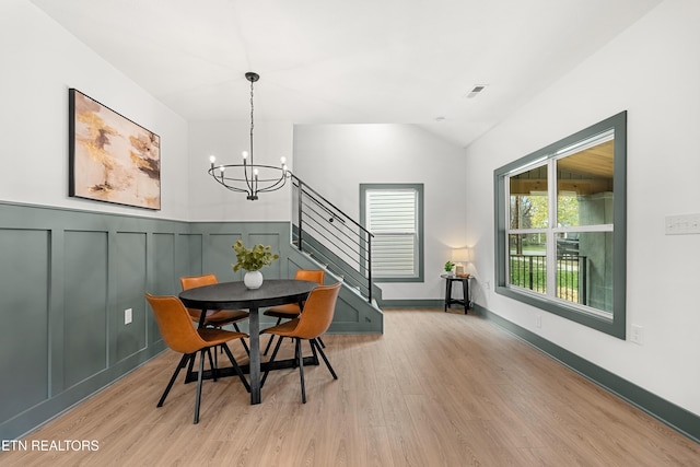 dining space featuring light wood-type flooring, lofted ceiling, and a chandelier