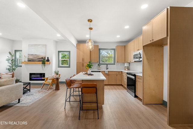 kitchen with stainless steel appliances, light hardwood / wood-style floors, a center island, pendant lighting, and light brown cabinets