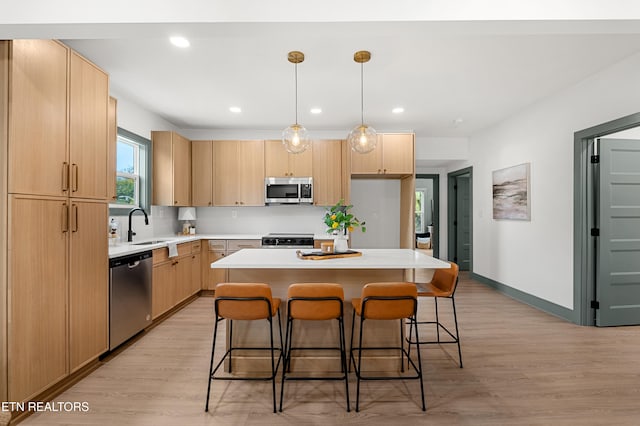 kitchen with light wood-type flooring, appliances with stainless steel finishes, light brown cabinetry, and a kitchen island