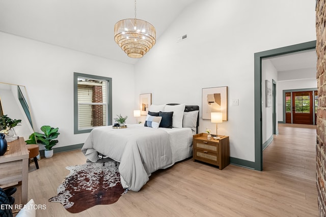 bedroom with light hardwood / wood-style floors, high vaulted ceiling, and a notable chandelier