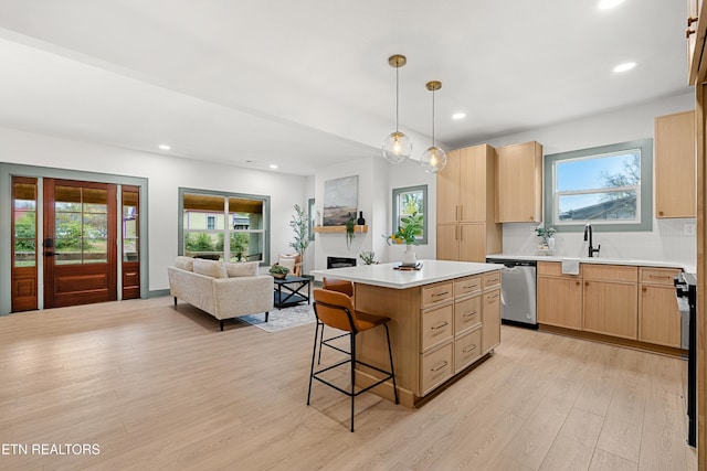 kitchen featuring plenty of natural light, stainless steel dishwasher, a center island, and light hardwood / wood-style flooring