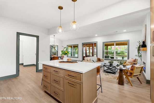 kitchen featuring light hardwood / wood-style floors, a notable chandelier, a kitchen island, a breakfast bar, and decorative light fixtures