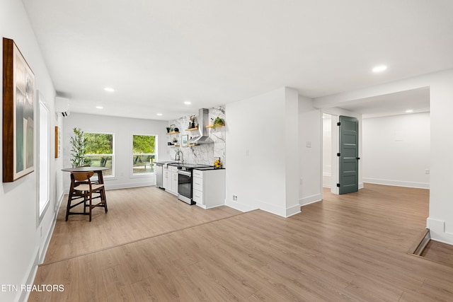 kitchen with appliances with stainless steel finishes, white cabinetry, light wood-type flooring, and range hood