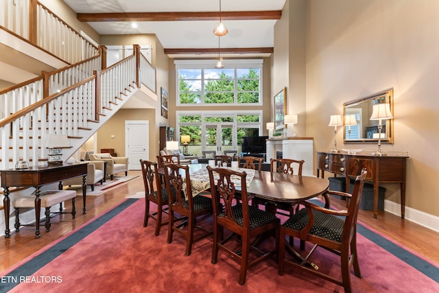 dining space featuring beamed ceiling, a towering ceiling, and dark hardwood / wood-style floors