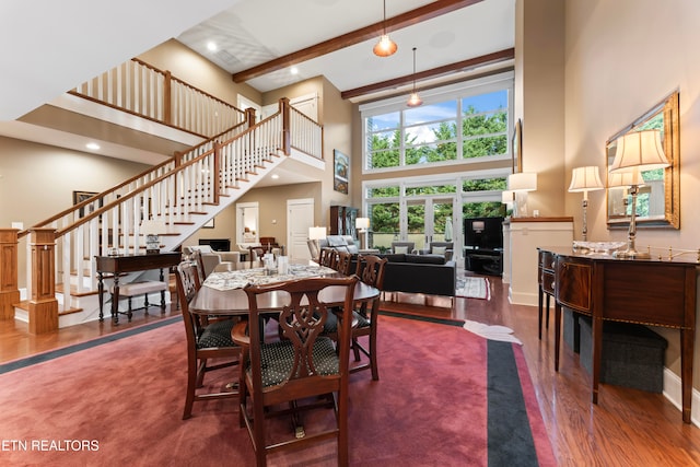 dining space with a towering ceiling, dark hardwood / wood-style floors, and beamed ceiling