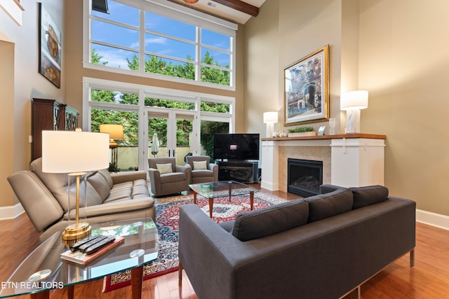 living room with wood-type flooring, a fireplace, and a high ceiling