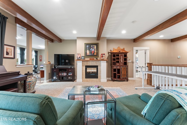 carpeted living room featuring a tiled fireplace and beam ceiling