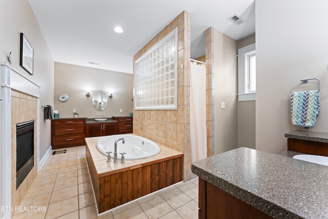 bathroom with tile patterned flooring, a tile fireplace, independent shower and bath, and vanity