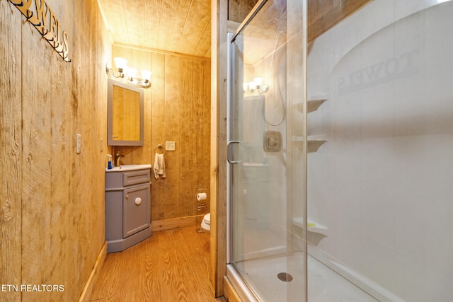 bathroom featuring hardwood / wood-style flooring, toilet, walk in shower, and wooden walls