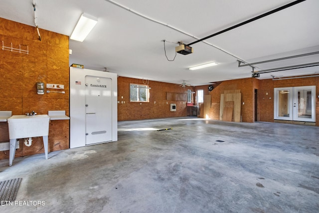 garage with sink, a garage door opener, and french doors