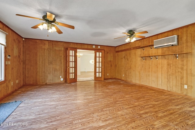 empty room featuring wooden walls, light hardwood / wood-style floors, a wall mounted AC, and french doors