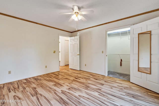 unfurnished bedroom with light wood-type flooring, a textured ceiling, ceiling fan, crown molding, and a closet