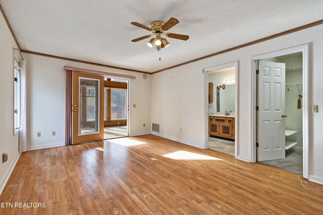 empty room featuring ceiling fan, ornamental molding, a textured ceiling, and light hardwood / wood-style flooring