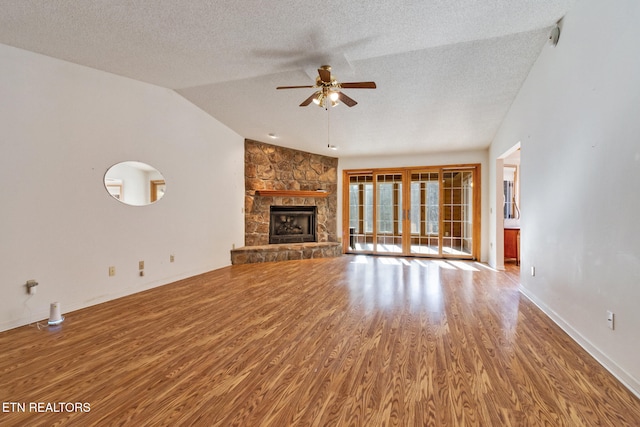 unfurnished living room with a textured ceiling, vaulted ceiling, ceiling fan, wood-type flooring, and a fireplace