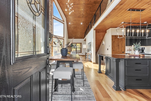 dining room featuring light wood-type flooring, high vaulted ceiling, wood ceiling, and an inviting chandelier