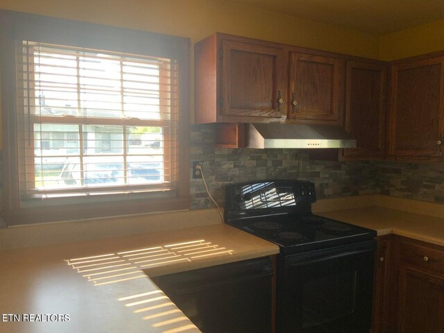 1315 Winchester Ave, Middlesboro, KY 40965 - kitchen with black electric range, wall chimney range hood, light countertops, and tasteful backsplash