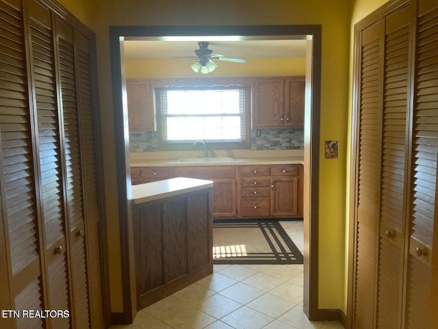 kitchen featuring light tile patterned floors, ceiling fan, sink, and tasteful backsplash