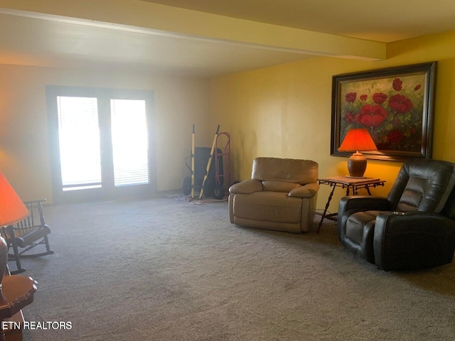 living area featuring beamed ceiling and carpet