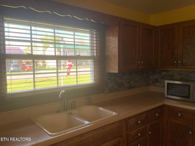 1315 Winchester Ave, Middlesboro, KY 40965 - kitchen featuring stainless steel microwave, a sink, healthy amount of natural light, and decorative backsplash