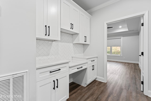 kitchen featuring dark hardwood / wood-style flooring, tasteful backsplash, ornamental molding, a raised ceiling, and white cabinetry