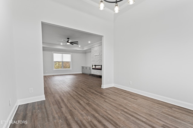 unfurnished living room with hardwood / wood-style floors, ceiling fan with notable chandelier, a fireplace, and crown molding