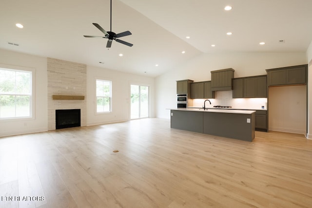 kitchen with light hardwood / wood-style floors, plenty of natural light, a center island with sink, and double oven